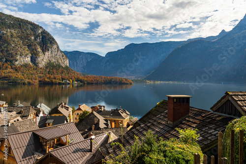 Alpine village overlooking mountain lake with autumn forest and cliffs