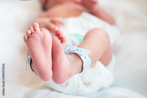 Newborn baby feet hospital bracelet soft skin gentle touch pastel light healthcare innocence closeup tenderness purity sleepy calm