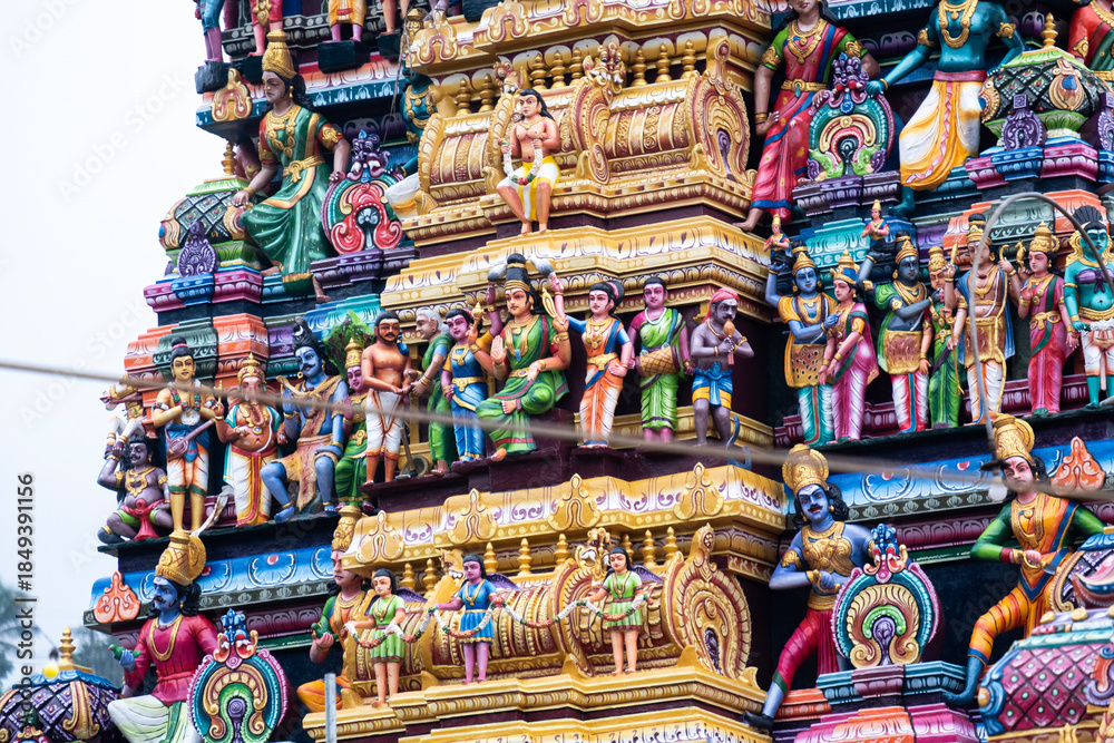 Fototapeta premium Decorative exterior details of a hindu temple in Matale, Sri Lanka. Colorful sculpted ornaments, traditional carvings and religious symbols showcasing South Asian spiritual architecture.