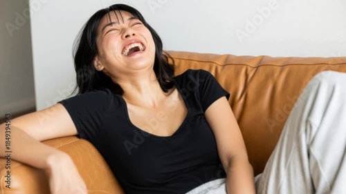 リビングのソファに深く座ってリラックスした笑顔を見せる若い女性