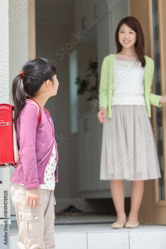 玄関先で見送る母親と娘