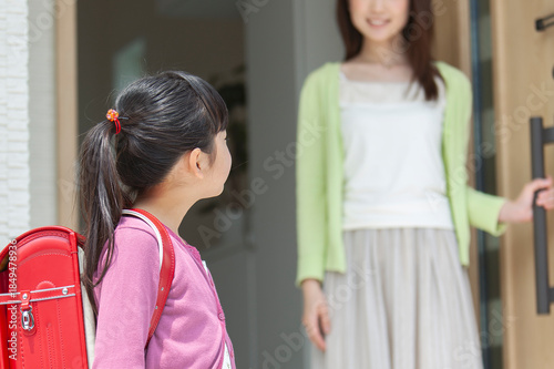 玄関先で見送る母親と娘