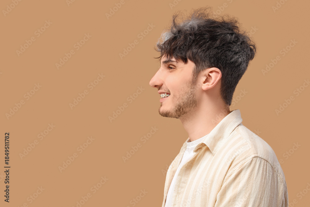 Fototapeta premium Young man with graying hair smiling on beige background