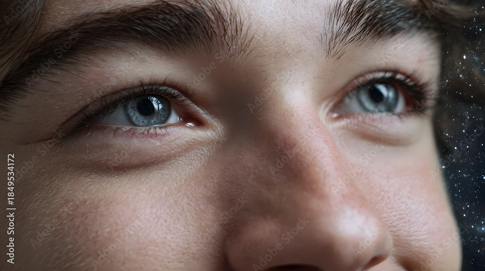 Fototapeta premium Close up of blue eyes gazing thoughtfully into a starry night sky reflecting wonder