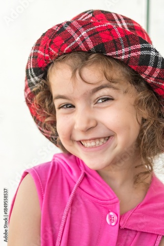 High resolution close up color portrait image of a young girl with a hat and a huge smile with a white background