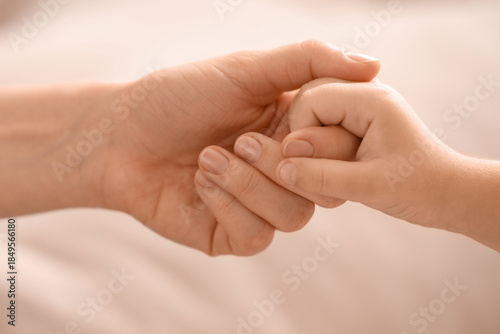 Foto Little girl with her mother holding hands at home, closeup