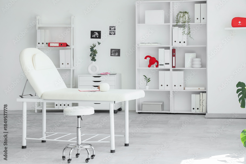 Fototapeta premium Interior of gynecologist's office with couch, shelf units and plants