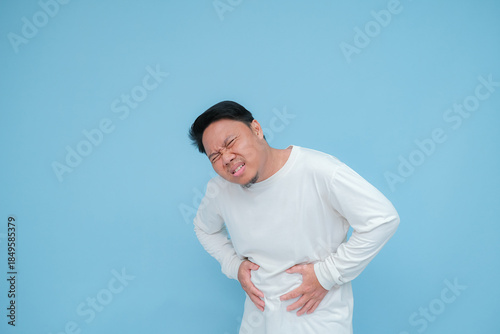 Bild auf Leinwand a young asian man has stomach ache hand expression when having stomach ache with