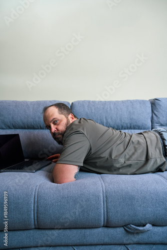 Man lying on couch using laptop