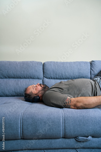Man rests on couch with headphones
