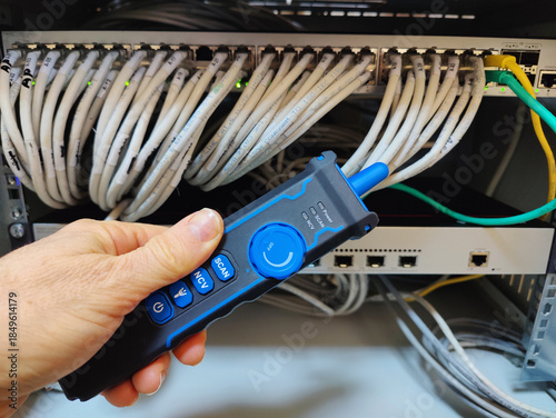 Technician Using a Digital Network Cable Tracker Probe to Identify and Test Ethernet Connections in a Server Rack Patch Panel
