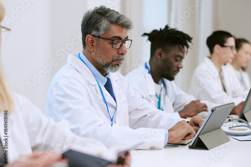 Photos Middle aged Caucasian man with gray hair sitting at desk using tablet computer a