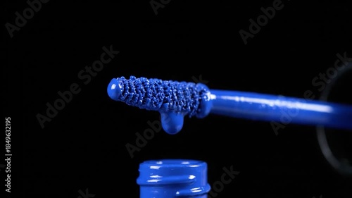 Detail of a vibrant blue cosmetic applicator dripping with thick blue liquid makeup
