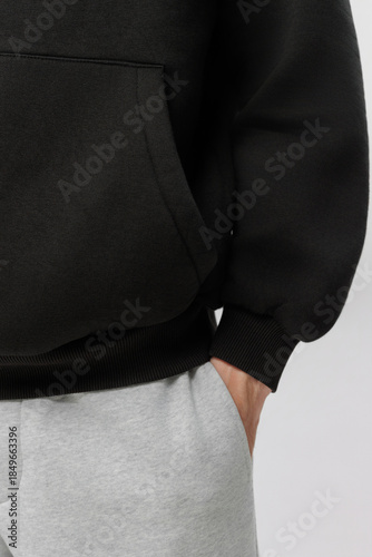 Black hoodie worn with gray sweatpants during indoor activity at home in daytime
