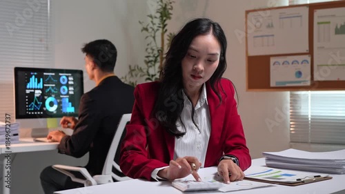 Frustrated businesswoman using calculator and checking time working late