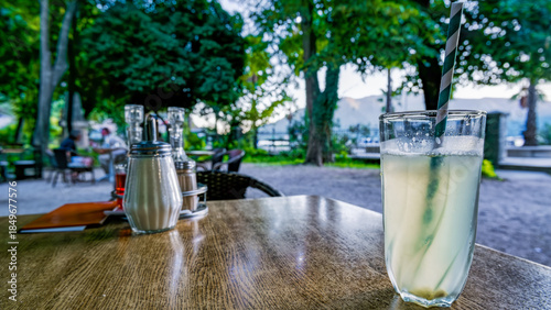 Bilde på lerret A refreshing drink sits on a wooden table in an outdoor café