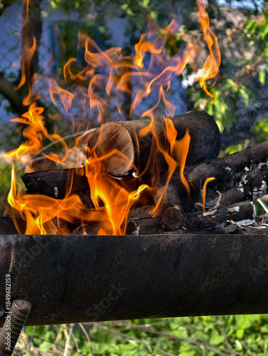 Burning firewood on outdoor grill, warm flames and rustic cooking atmosphere.