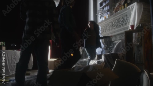 Handheld following shot of young people entering abandoned house holding flashlights and settling down in secret hideout, focus flowing from legs to full length view scene