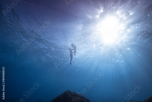 Couple celebrating pregnancy underwater with dance in apnee