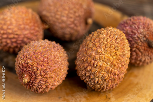 Fotografie ripe red lychees scattered on a wooden table, ripe red-skinned lychee fruits,rou