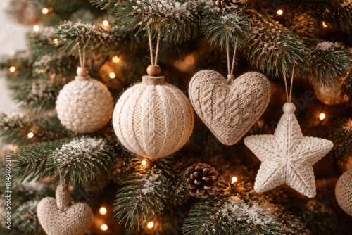 Close up festive decor scene of knit texture ornament hanging on an evergreen branch. neutral color palette creates warm, peaceful, and cozy holiday mood