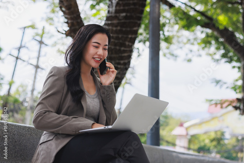 Young woman confidently working remotely using laptop and phone