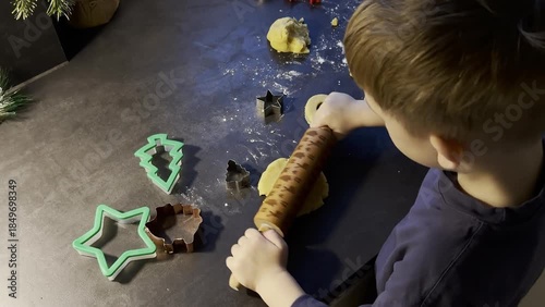 Top view of a boy making cookies from shortcrust pastry, Christmas themed bake at home 