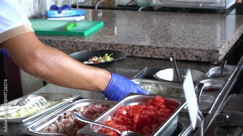 A chef prepares food in a restaurant. He adds chopped tomatoes, chopped onions, bell peppers, and mushrooms to a hot frying pan. Slow motion video. Perfect for cooking and food preparation content.