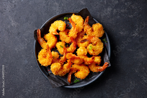 Crispy prawns on dark plate, tempting seafood appetizer for menu showcase. Grey background. Close up. Top view.