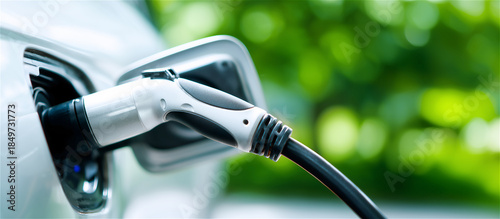 Close-up of an electric vehicle charging connector plugged in, symbolizing e-mobility and decarbonization. Clean transport technology concept for sustainability, innovation, and future energy.