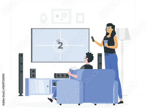Woman holding phone and drink standing next to man sitting on blue couch watching tv with popcorn de