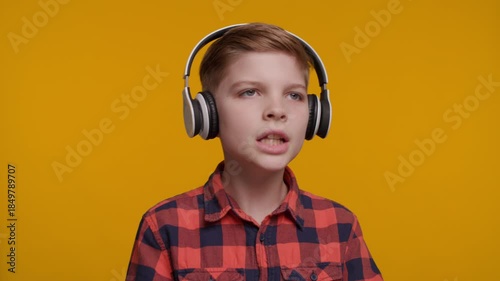 Boy in Headphones Singing at Camera on Yellow Background