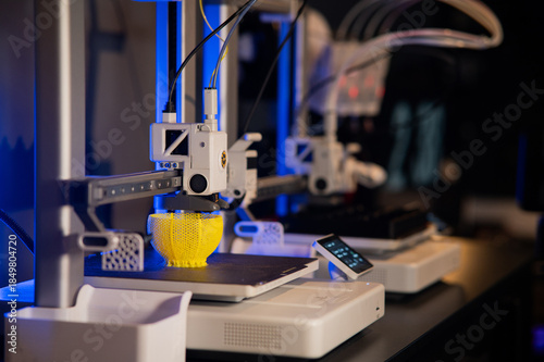 Modern 3D printer printing a yellow lattice sphere object. Process of additive manufacturing and rapid prototyping in a high-tech workshop.