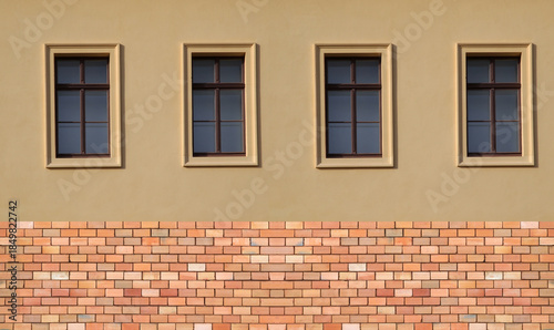 Hausfassade mit vier Fenstern und Klinkersockel