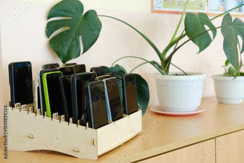 Bilde på lerret Schoolchildren's mobile phones neatly organized in a wooden box on a classroom s