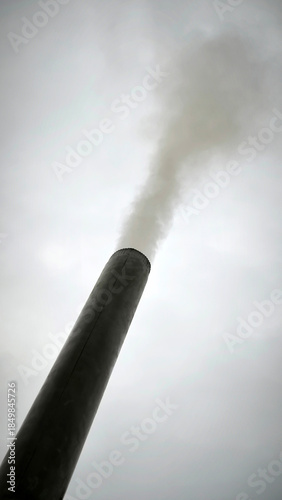 old metal chimney on the roof with grey smoke coming out