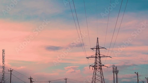 High-Voltage Electric Pole and Time Lapse of Orange Peach Clouds and Blue Sunset Sky Time Lapse 4K. Transmission Tower, Electric Line, High-Voltage Transmission Line, Overhead Power Line.