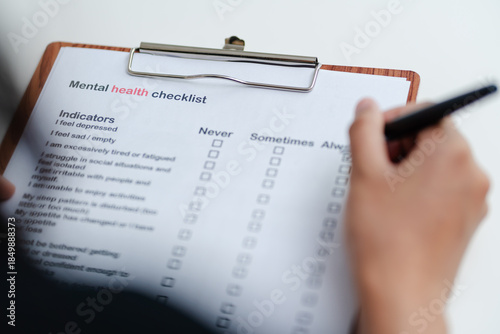 Person filling mental health checklist on clipboard with pen, psychological assessment, self evaluation, healthcare screening and wellbeing awareness concept.