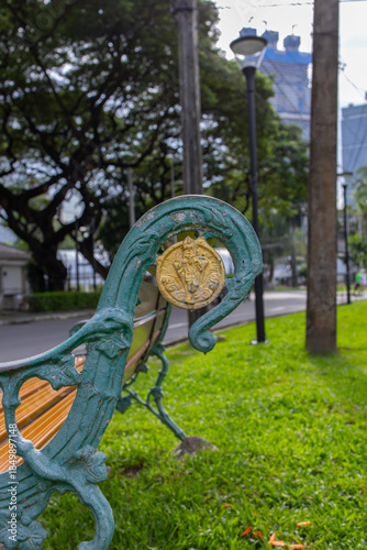 Street bench side view, with curved iron bench frame in green with twisted floral decorative elements