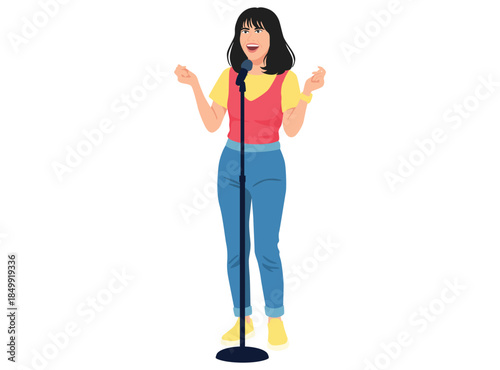 smiling female performer with dark hair stands at a microphone, energetically gesturing while singing or doing stand up comedy.