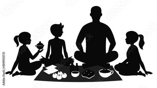 Family sitting on a picnic blanket eating and meditating together in silhouette