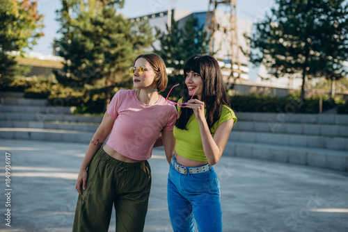 Stylish girlfriends rests after quad skating in urban park

