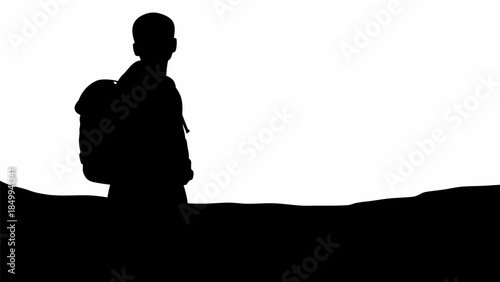 Silhouette of a young traveler with backpack standing alone