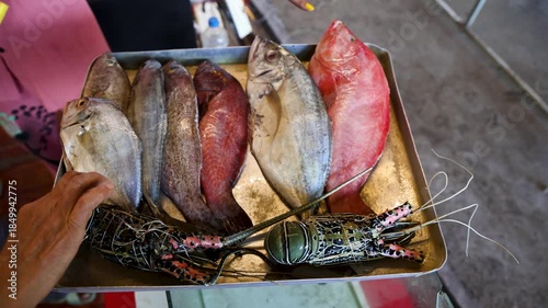 fresh whole fish and lobster on tray at seafood market