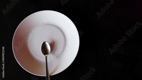 empty white plate with spoon on black background minimal concept