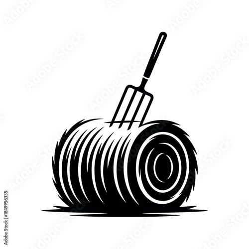 A pitchfork is stuck into a large bale of hay.