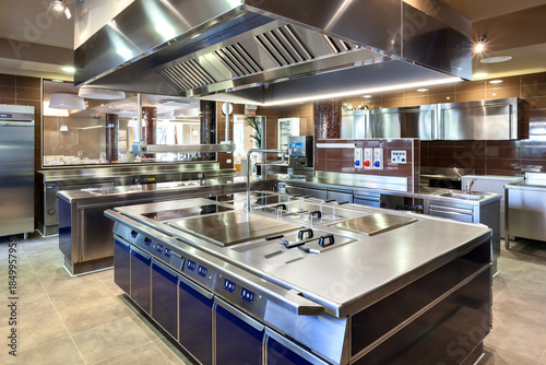 Modern industrial kitchen with induction island, sinks, ventilation hood, and stainless appliances—ideal for culinary operations.