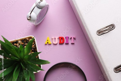 Word audit on purple background with office accessories. Business concept. Top view