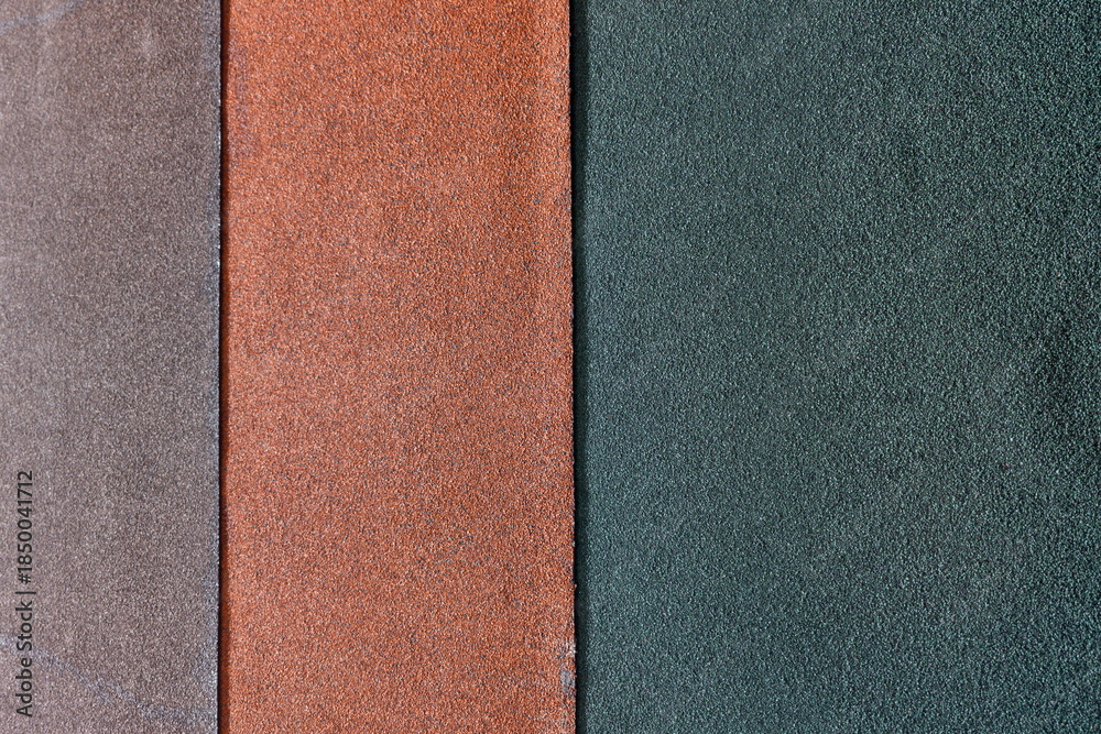 Fototapeta premium Different colors of sandpaper laid out side by side on a flat surface for viewing texture and material properties in a workspace setting