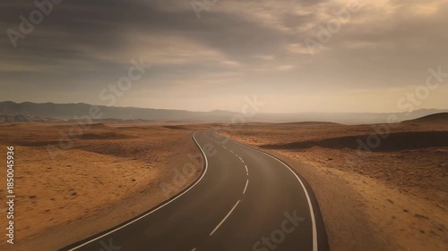 Desert road leading to horizon under cloudy sky daytime